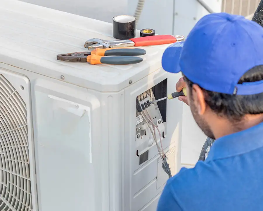 A Precision Climate Control technician in a blue cap performs AC Repair Services to Restore Cooling Fast to AC unit in St. Charles, MO, with tools resting on top