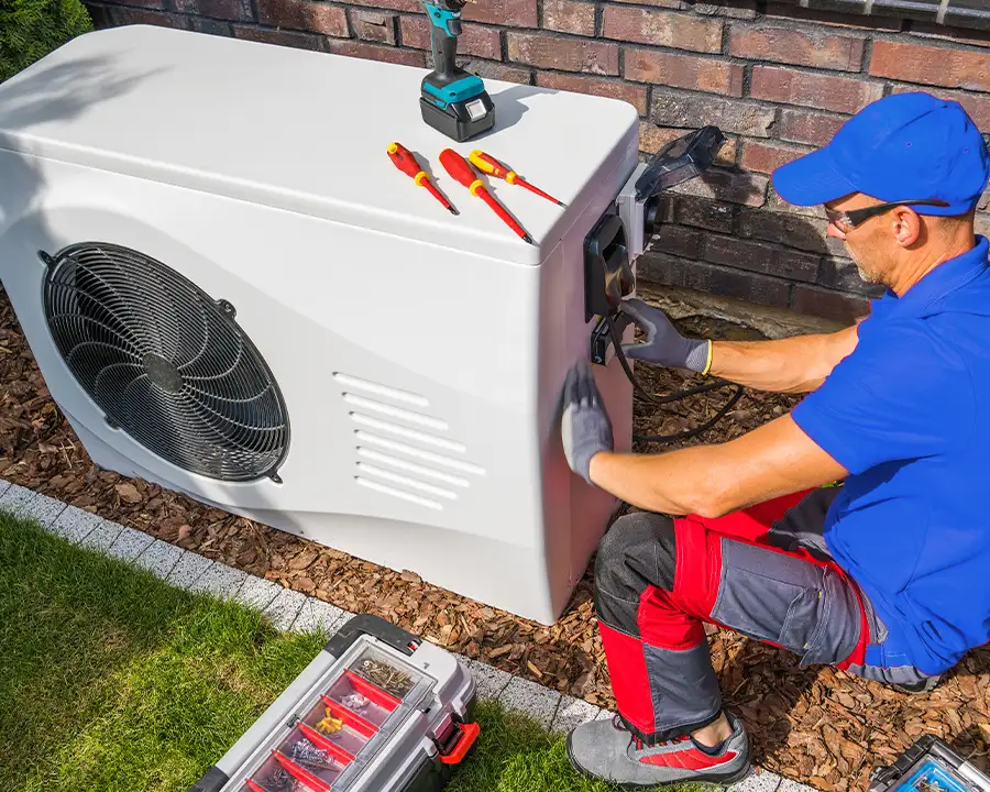 A Precision Climate Control technician in a blue uniform performing Installation/Replacement of Heat Pump Systems in St. Charles, MO