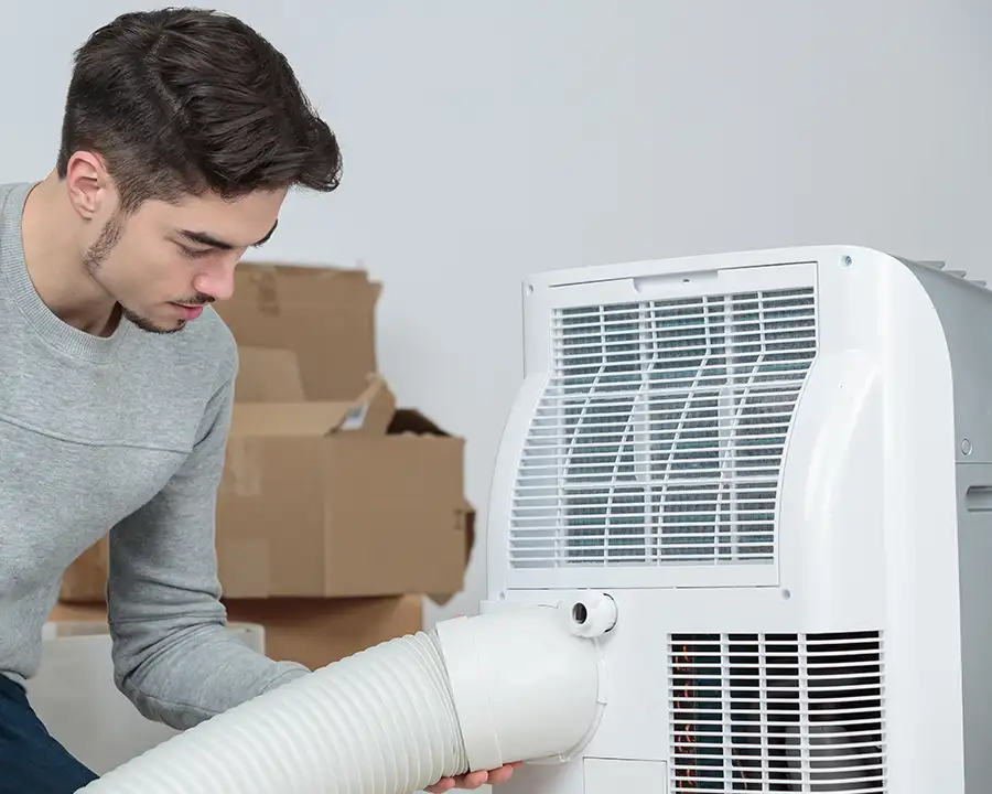 Young man installing a whole-home Dehumidifier System for Moisture Control in his St. Charles, MO home as recommended by Precision Climate Control